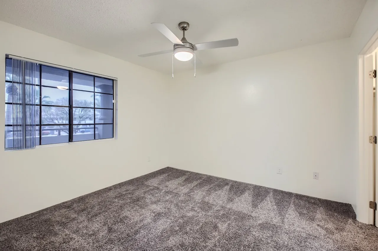 Bedroom, gray carpet flooring, ceiling fan with light fixture, large multi-pane window