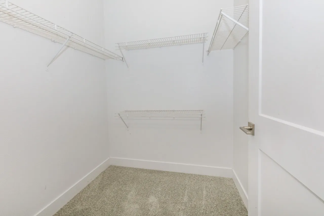 Walk-in closet, wire shelving, berber carpet flooring, white walls