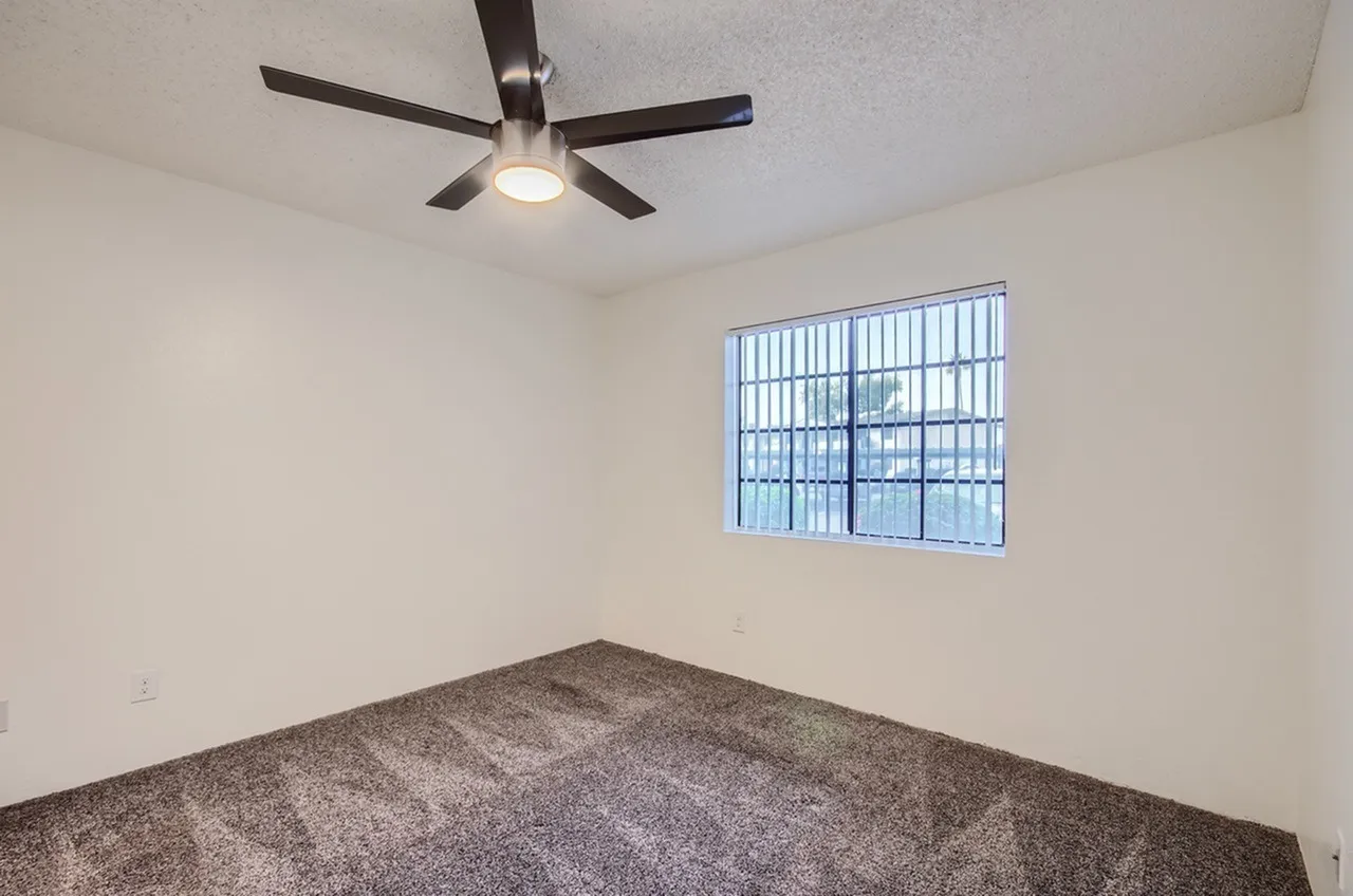 Bedroom, carpet flooring, ceiling fan with light, window with security bars