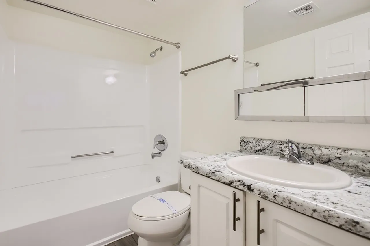 Bathroom, marble countertops, white vanity cabinetry, glass shower enclosure, toilet