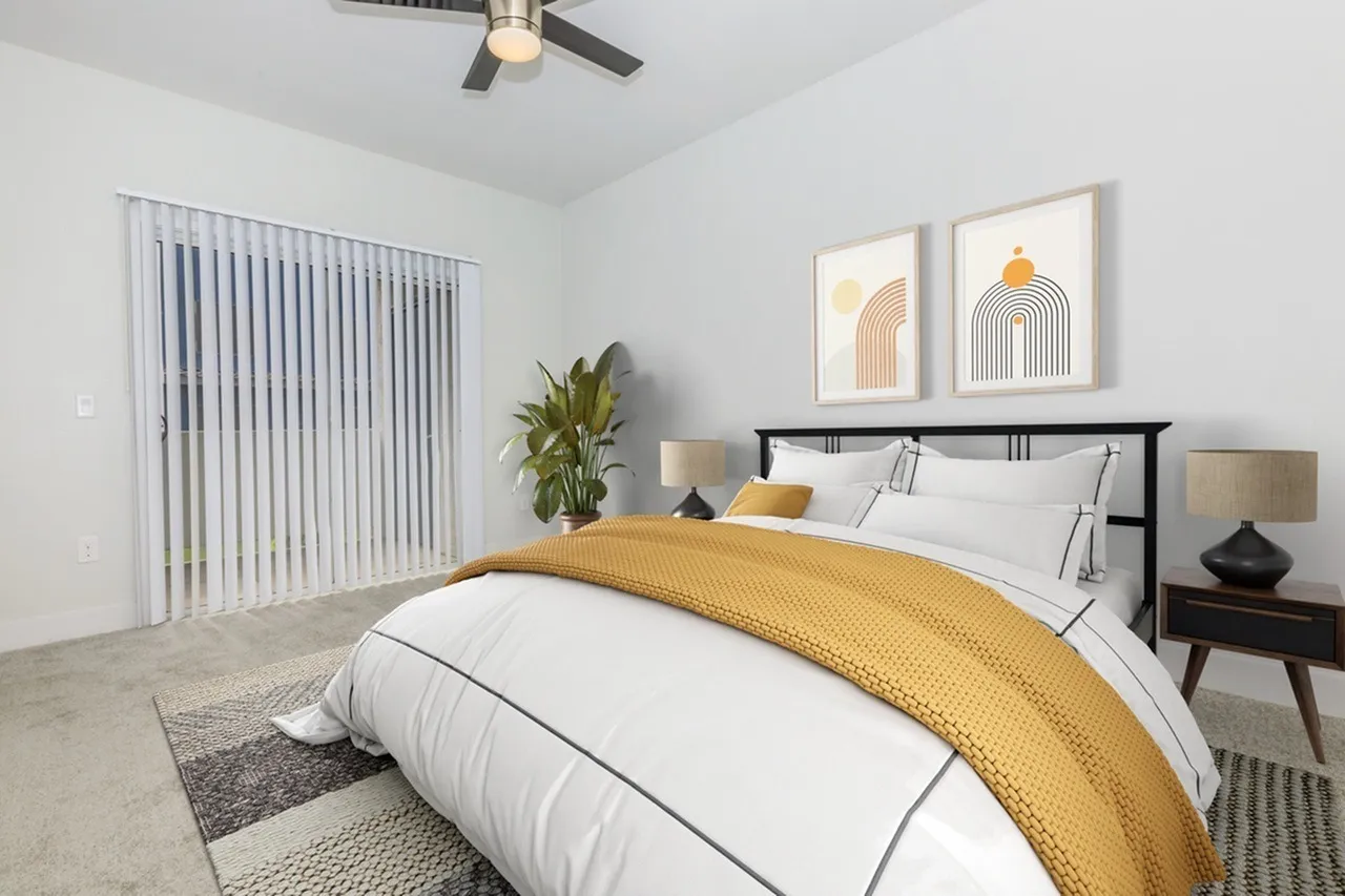 Primary bedroom, wood-style plank flooring, black headboard, yellow bedding, artwork, ceiling fan