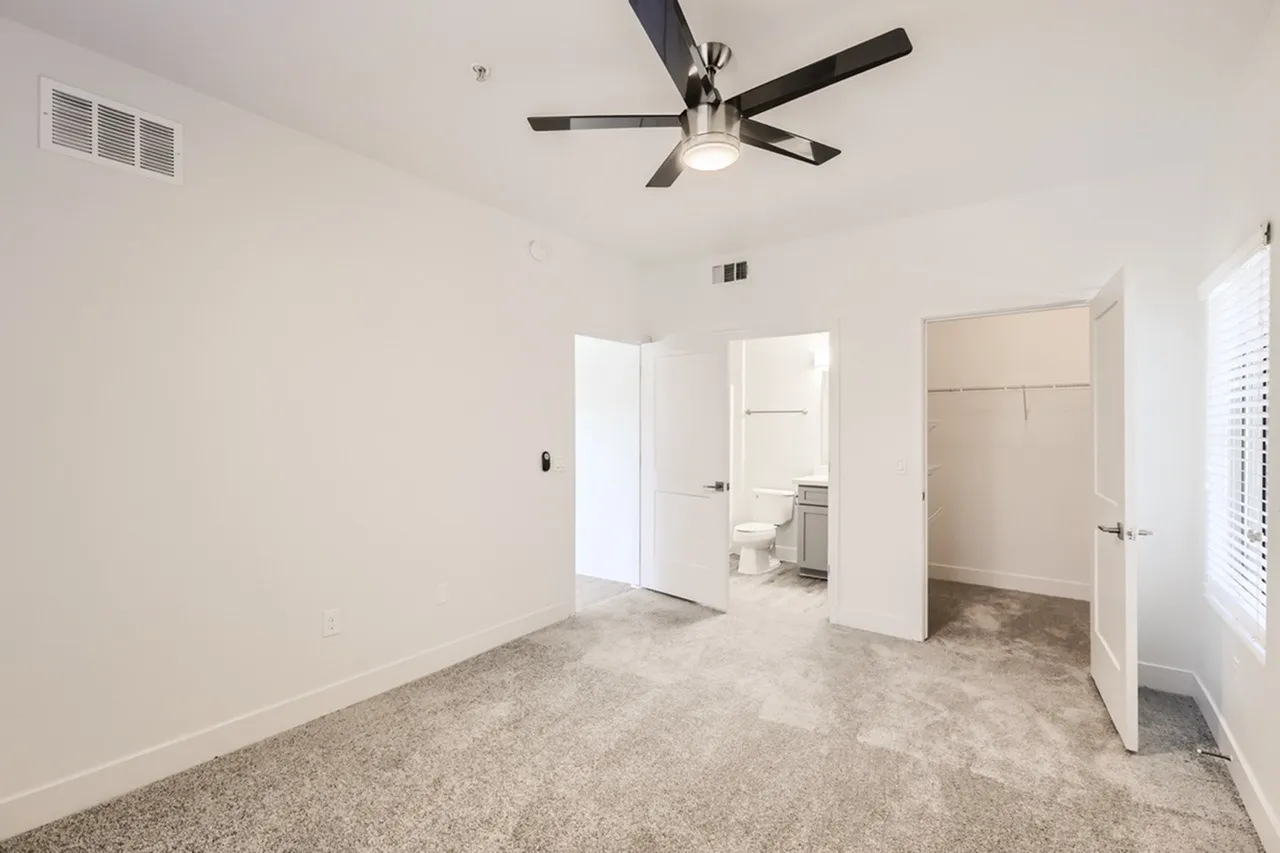 Primary bedroom, carpet flooring, ceiling fan, ensuite bathroom with toilet visible