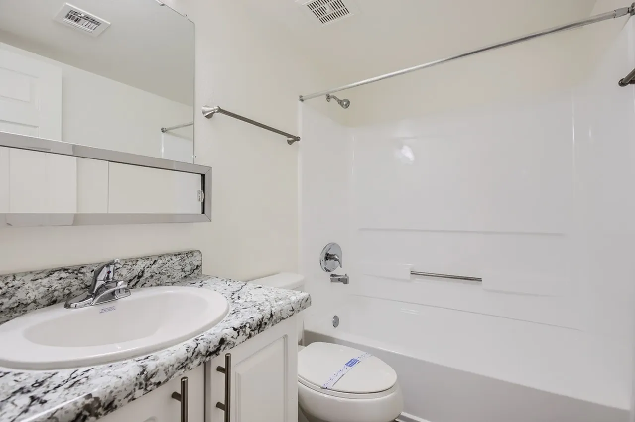 Bathroom, speckled granite countertops, white cabinetry, round vessel sink, soaking tub