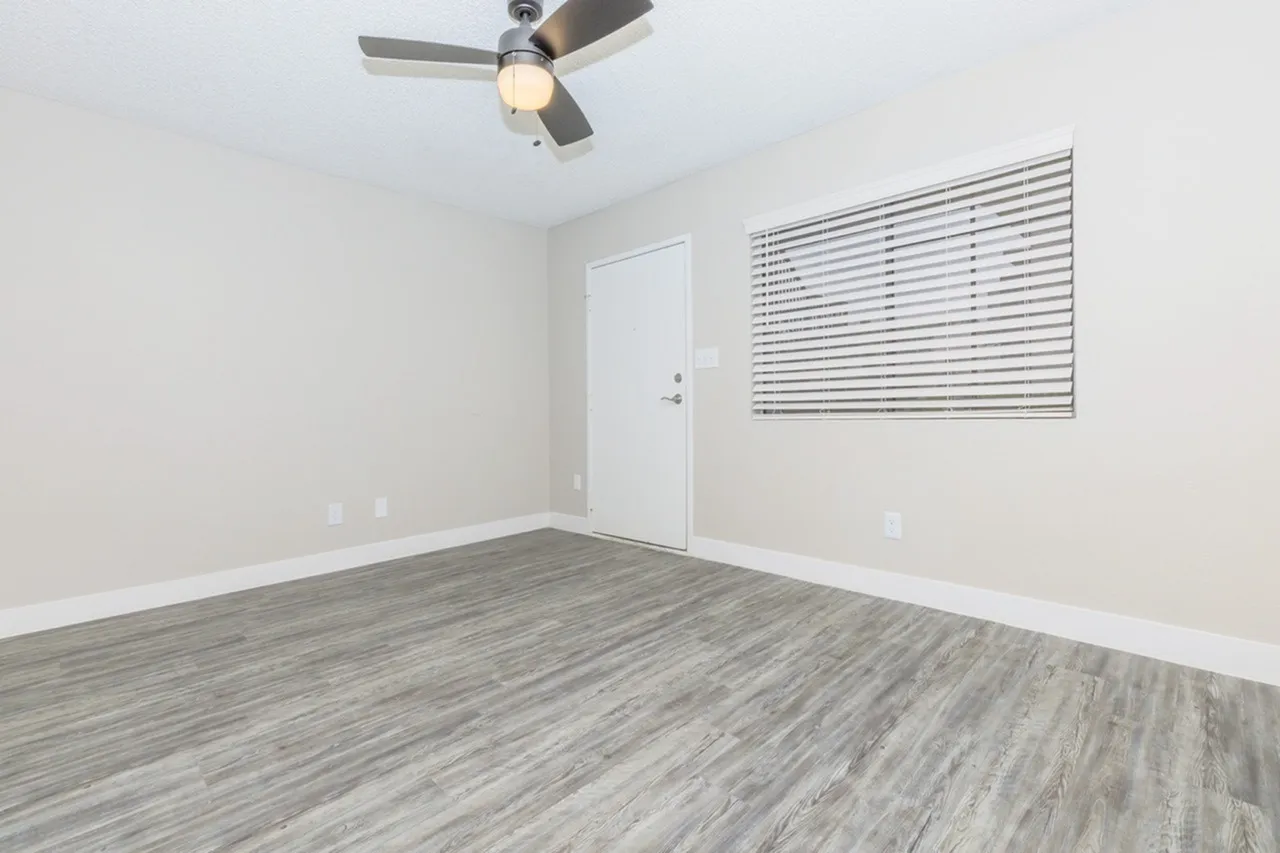 Bedroom, wood-style plank flooring, ceiling fan with light, horizontal blinds, entry door