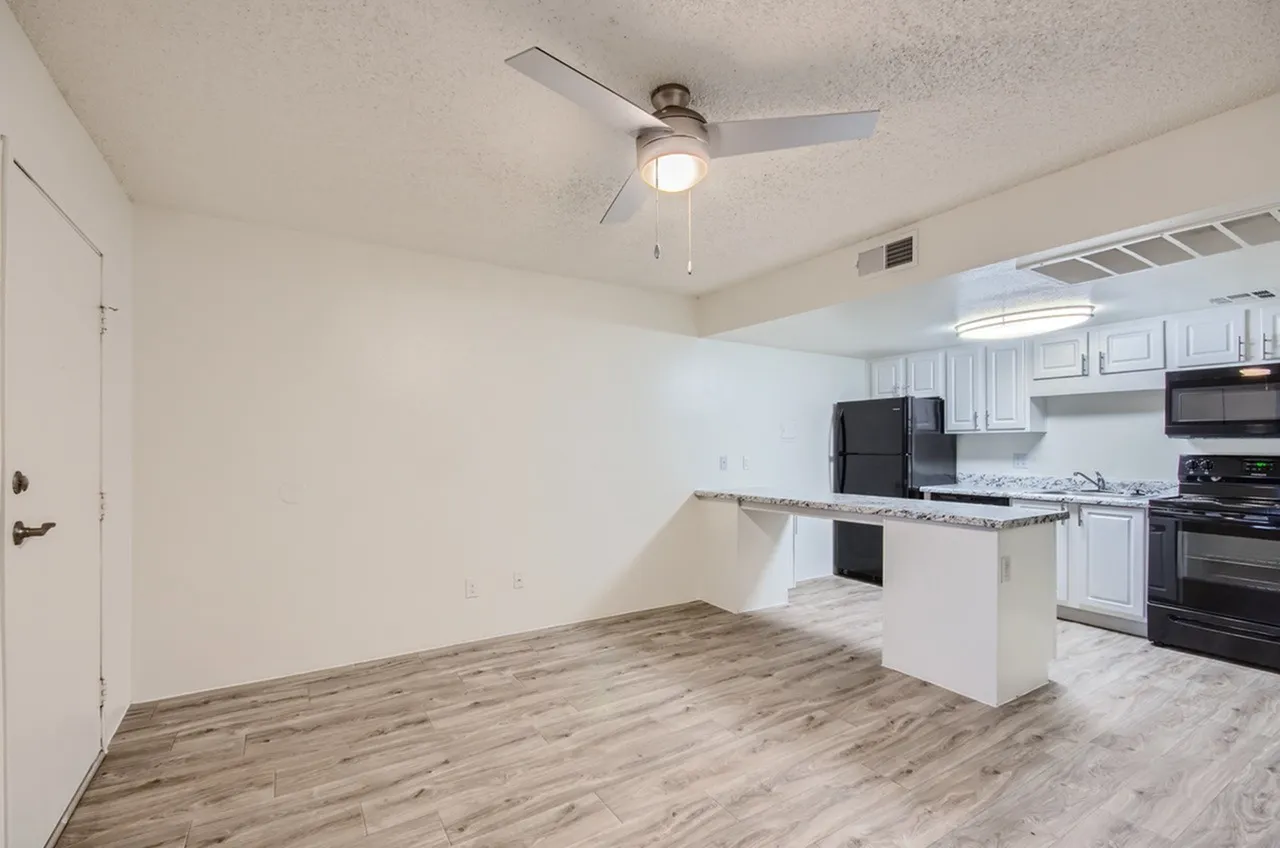 Kitchen, white shaker cabinetry, black appliances, wood-style plank flooring, ceiling fan