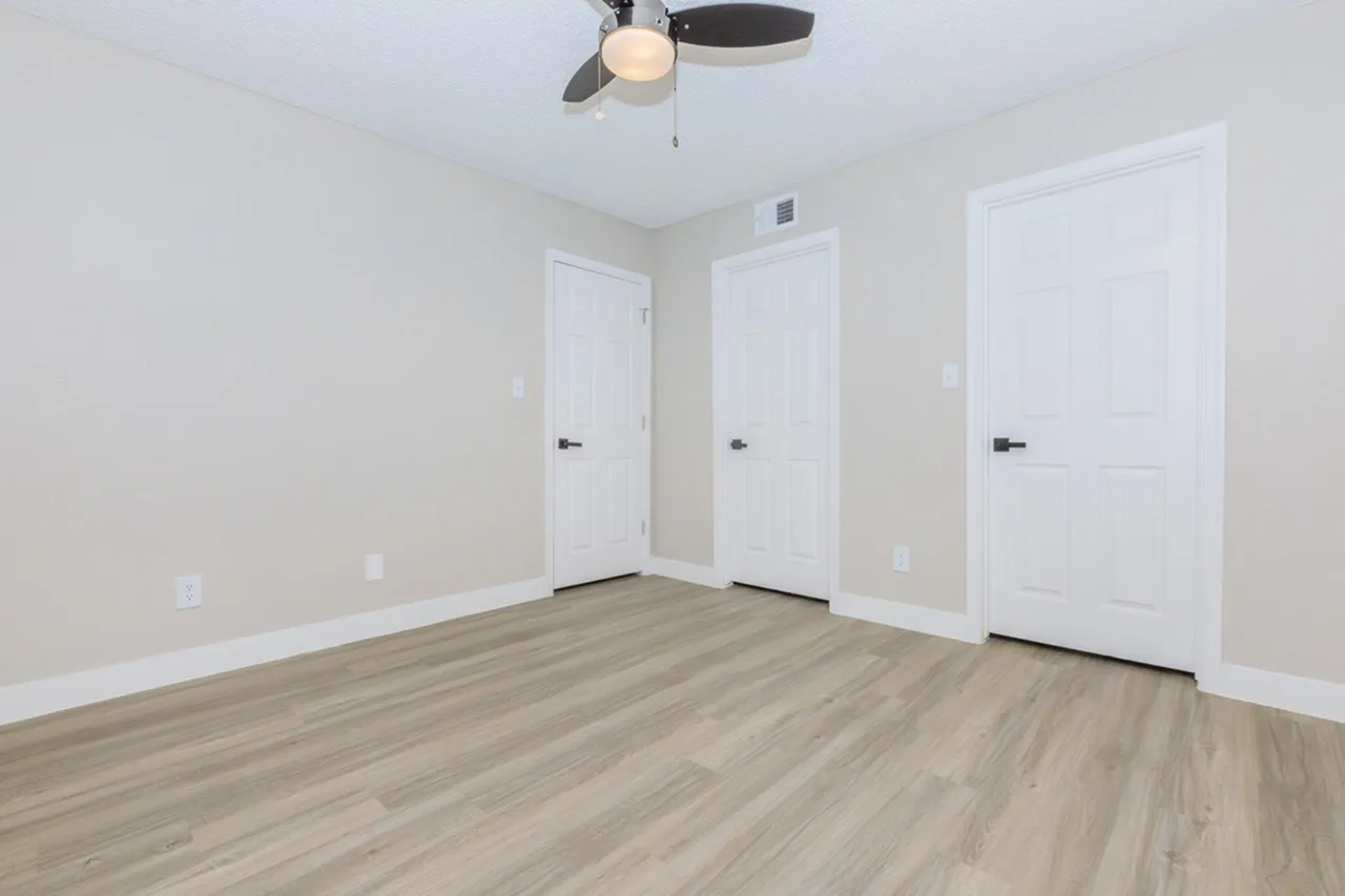 Bedroom, wood-style plank flooring, white entry doors, ceiling fan