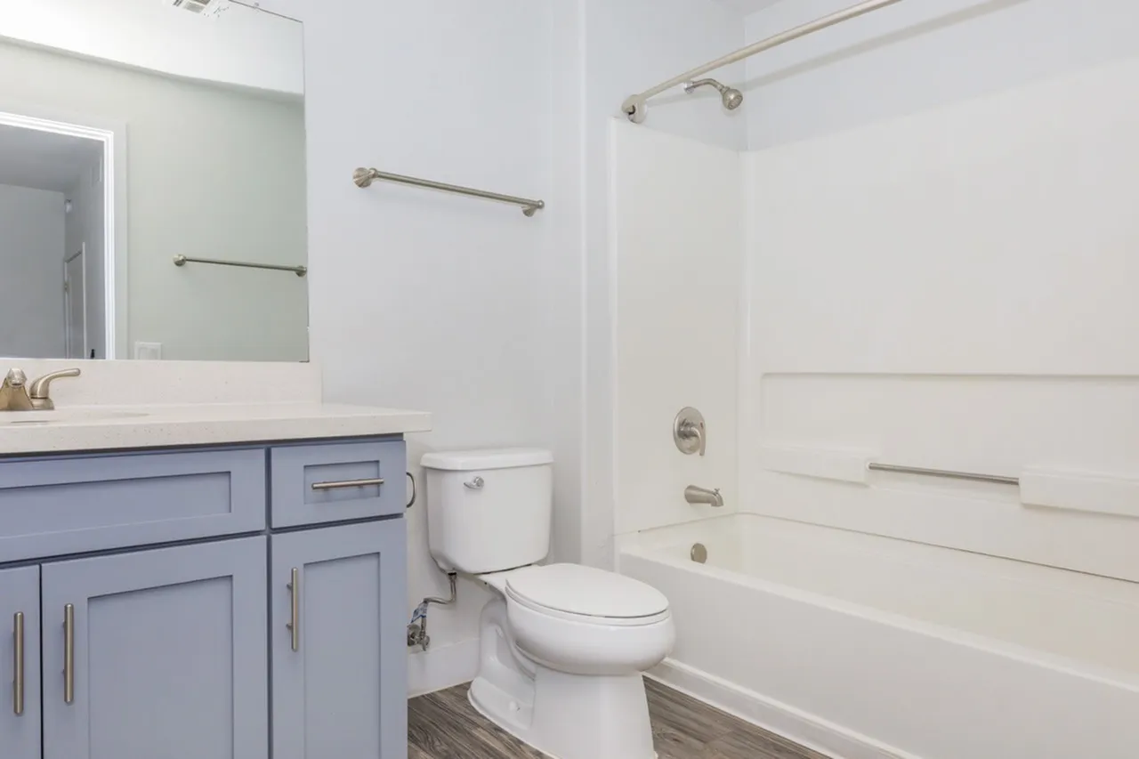 Bathroom, blue vanity cabinetry, white countertops, white tile bathtub surround