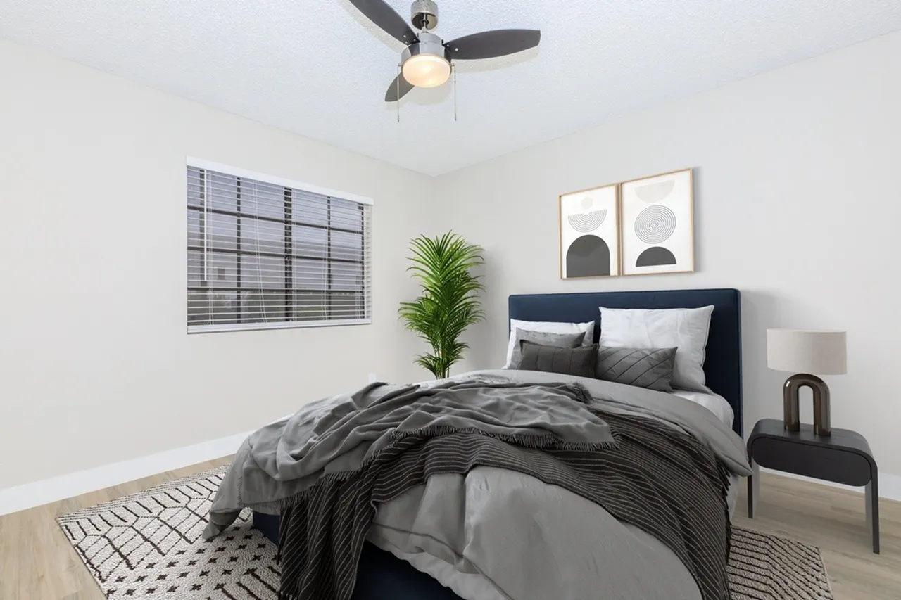 Primary bedroom, navy upholstered headboard, wood-style plank flooring, ceiling fan, geometric wall art