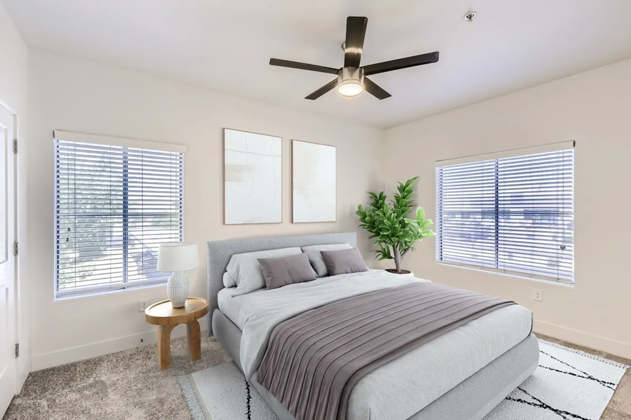 Primary bedroom, gray upholstered headboard, striped bedding, ceiling fan, shuttered windows