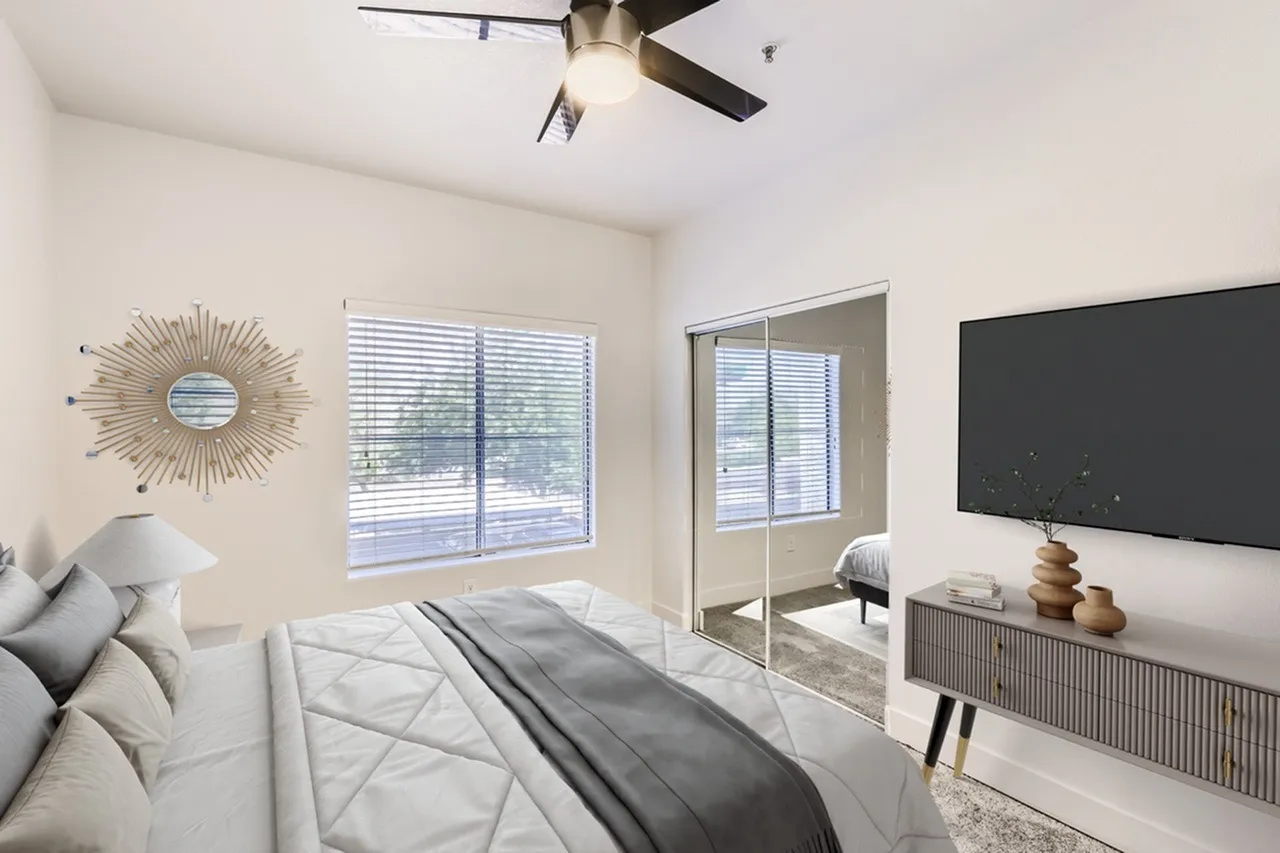 Primary bedroom, wood-style plank flooring, ceiling fan, wall-mounted television, modern decor
