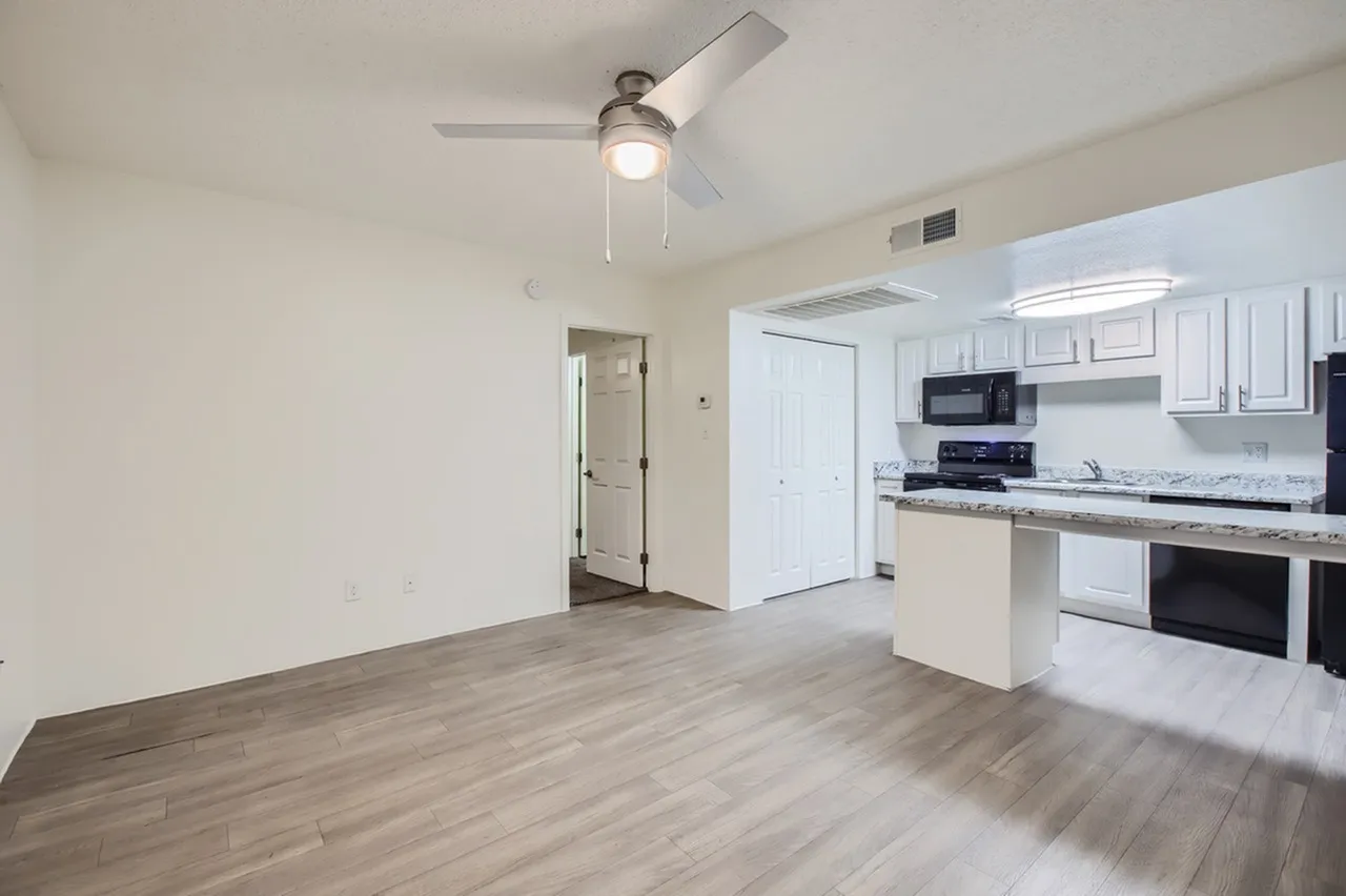 Kitchen and living room, wood-style plank flooring, white cabinetry, stainless appliances, ceiling fan