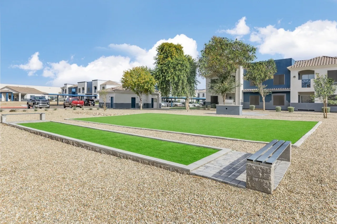 Common courtyard with manicured lawn, mature trees, architectural water feature, landscaping, surrounding residential buildings