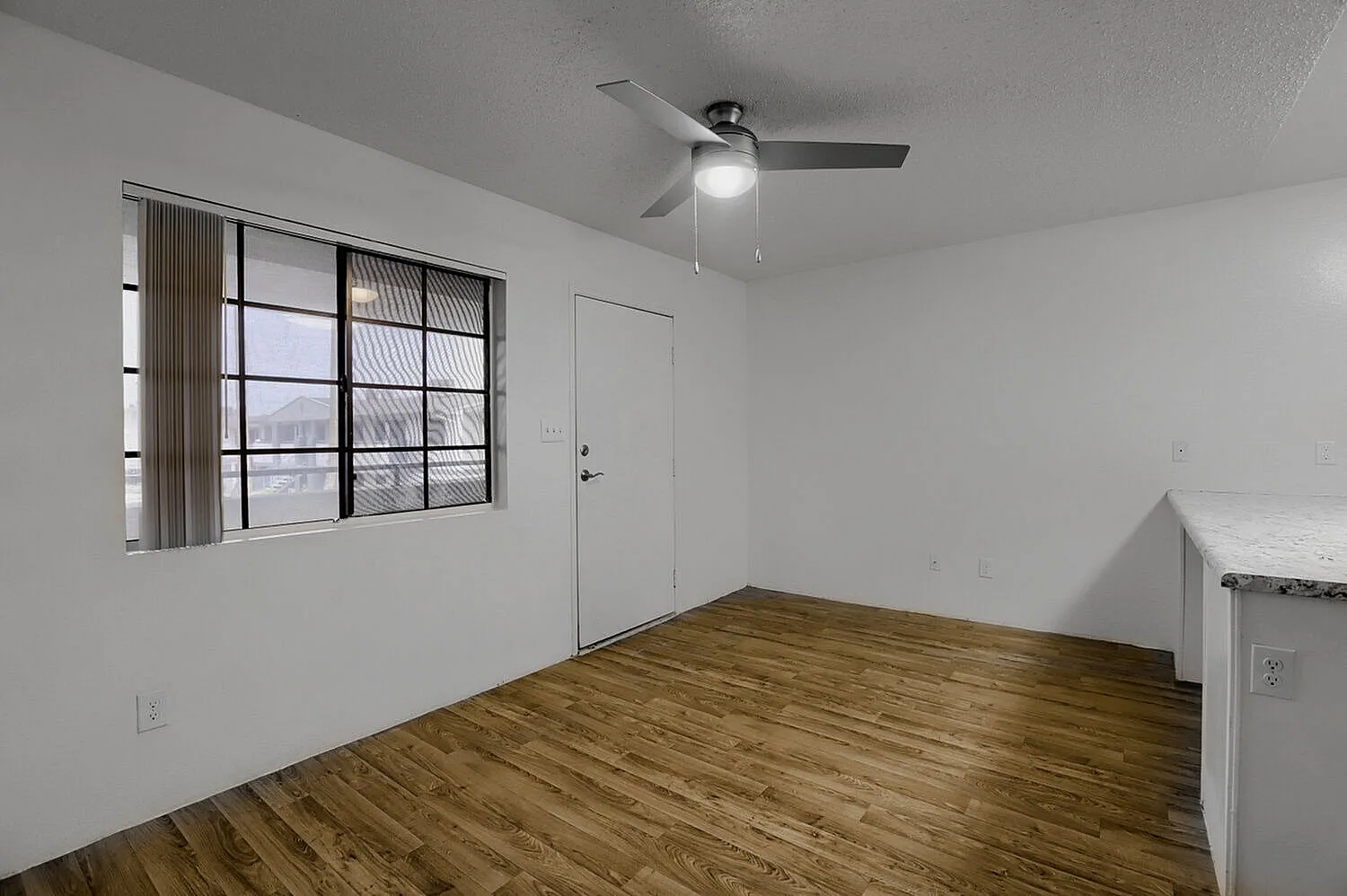 Bedroom, wood-style plank flooring, ceiling fan with light, large window, entry door