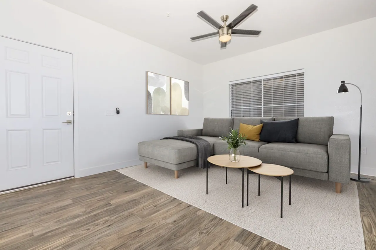 Living room, gray sectional sofa, wood-style plank flooring, ceiling fan, entry door