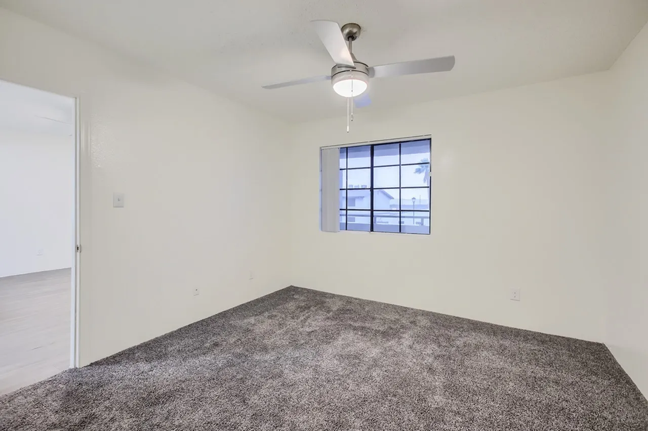Bedroom, gray carpet flooring, ceiling fan with light, blue-trim window