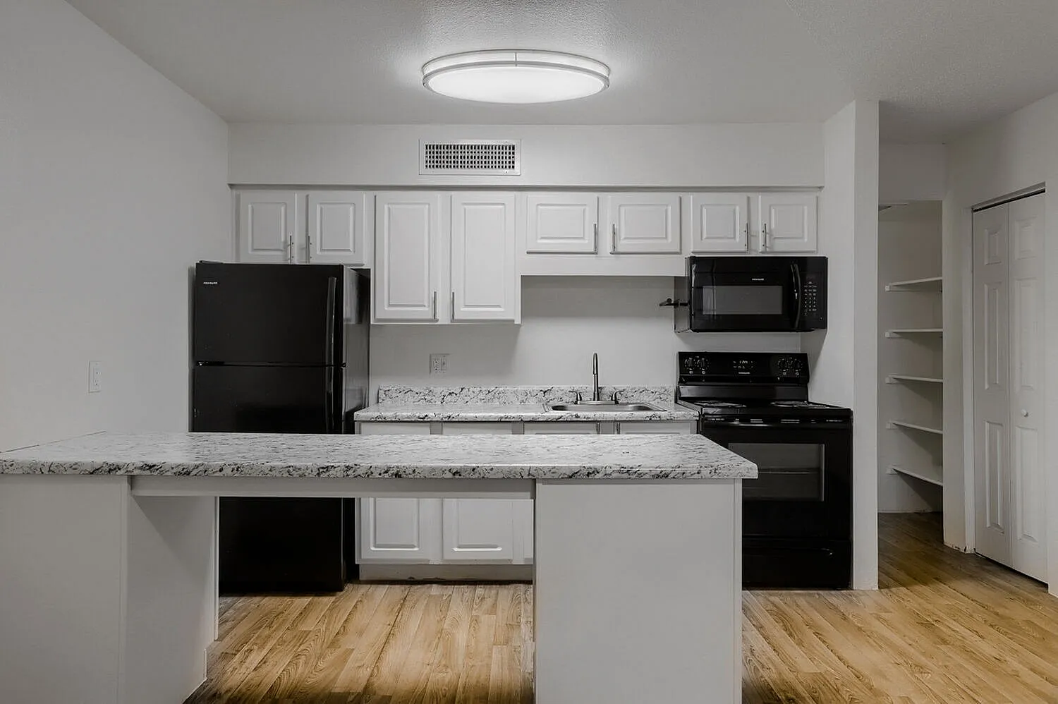 Kitchen, white shaker cabinetry, speckled quartz countertops, black appliances, wood-style plank flooring
