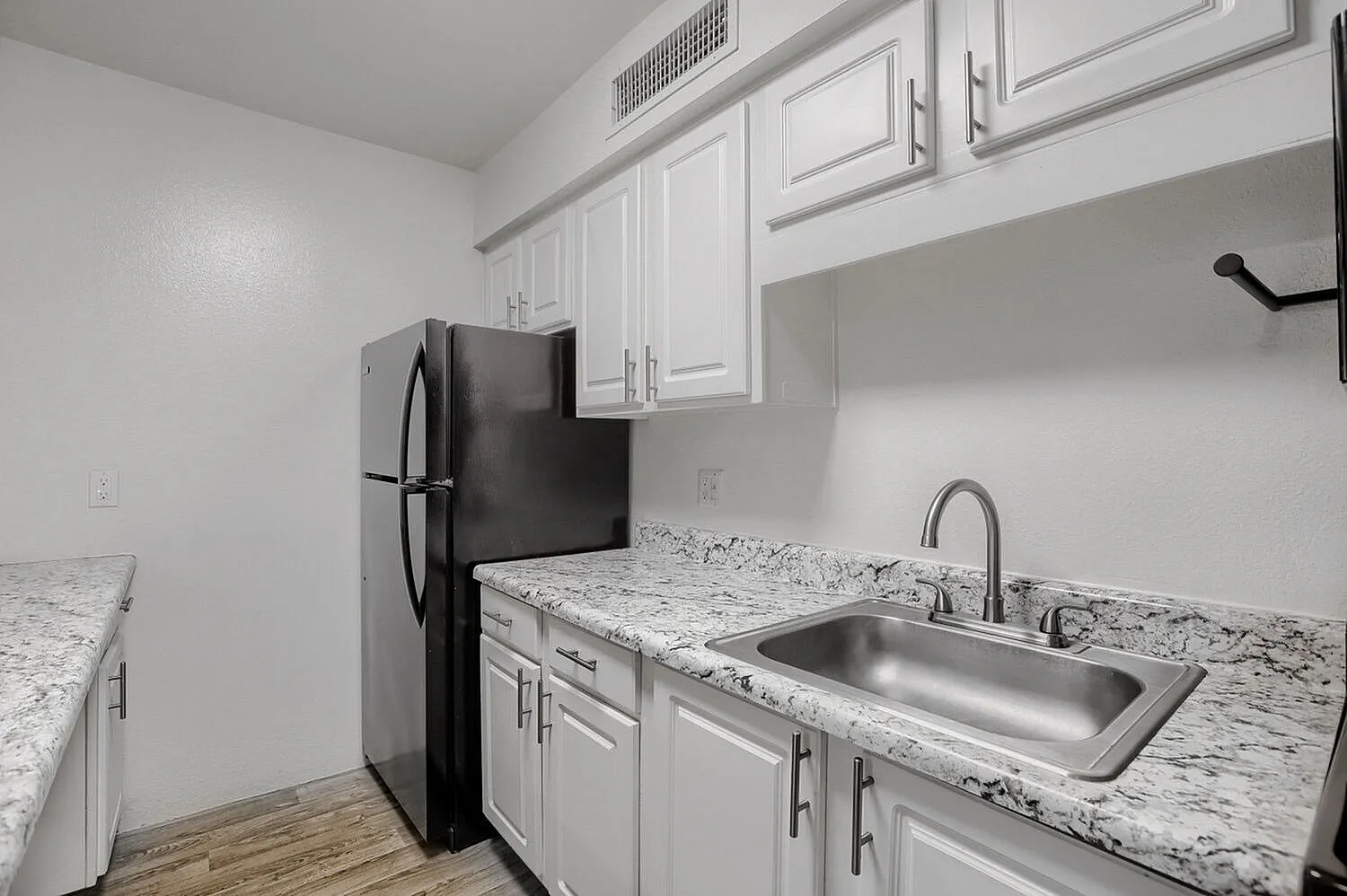 Kitchen, white shaker cabinetry, granite countertops, stainless steel sink, black refrigerator, wood-style plank flooring