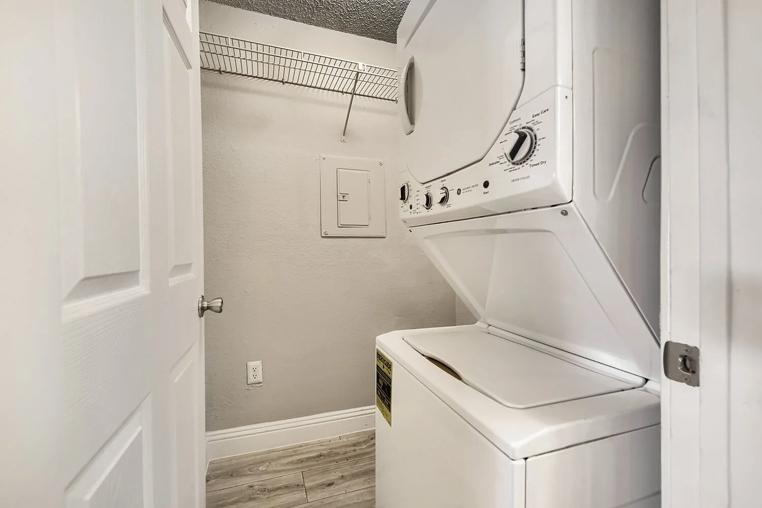 Laundry closet, stacked washer and dryer, wire shelving, electrical panel