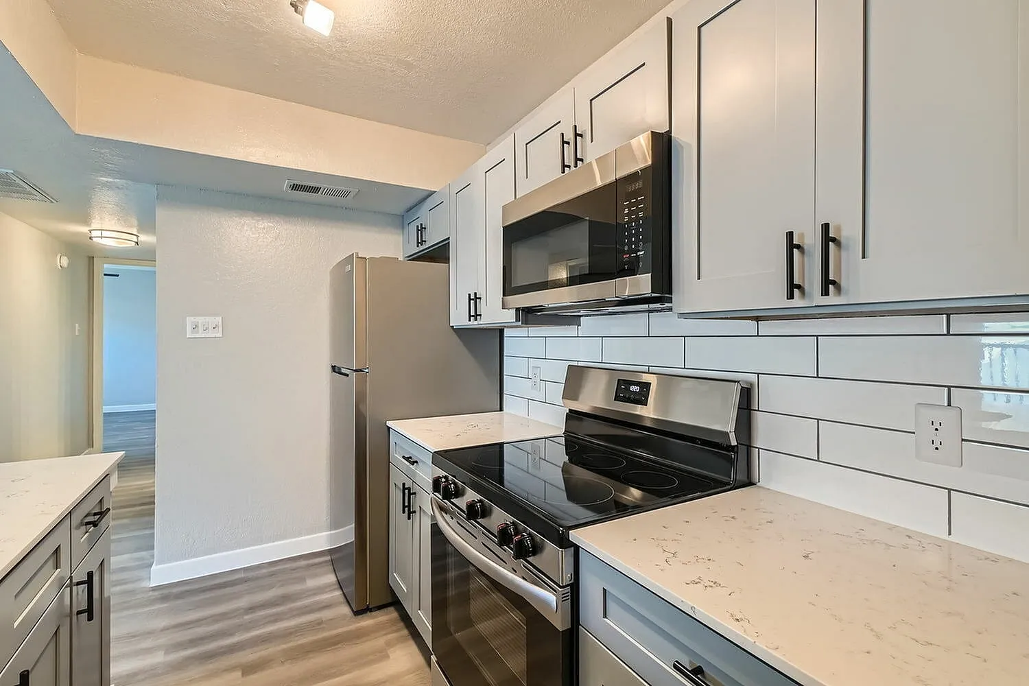 Kitchen, gray cabinetry, quartz-style countertops, subway tile backsplash, stainless steel appliances, glass-top range
