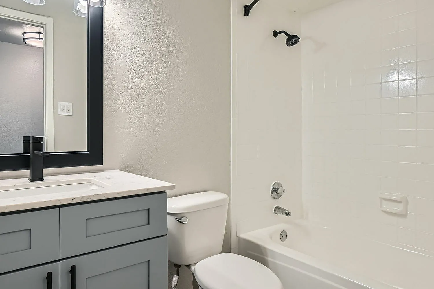 Bathroom, tub shower, gray vanity cabinet, quartz-style countertop, white toilet