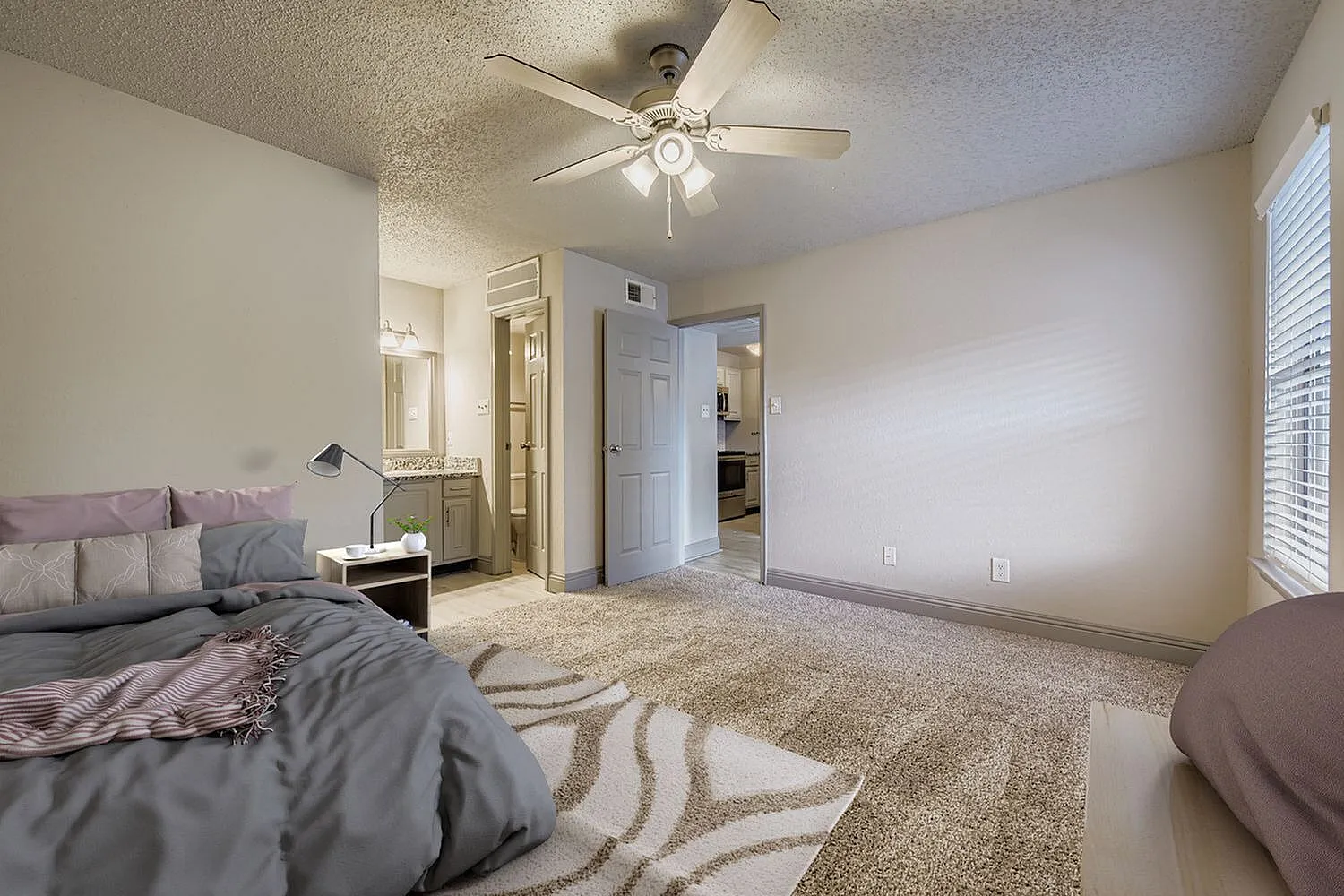 Bedroom, ceiling fan, carpet flooring, doorway to bathroom