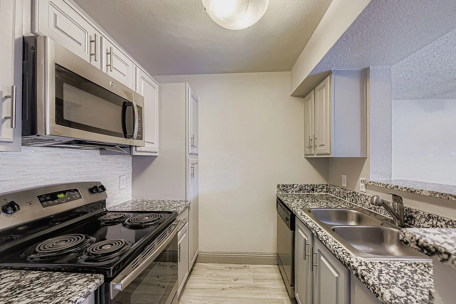 Kitchen, electric coil range, over-range microwave, speckled countertop, double basin sink