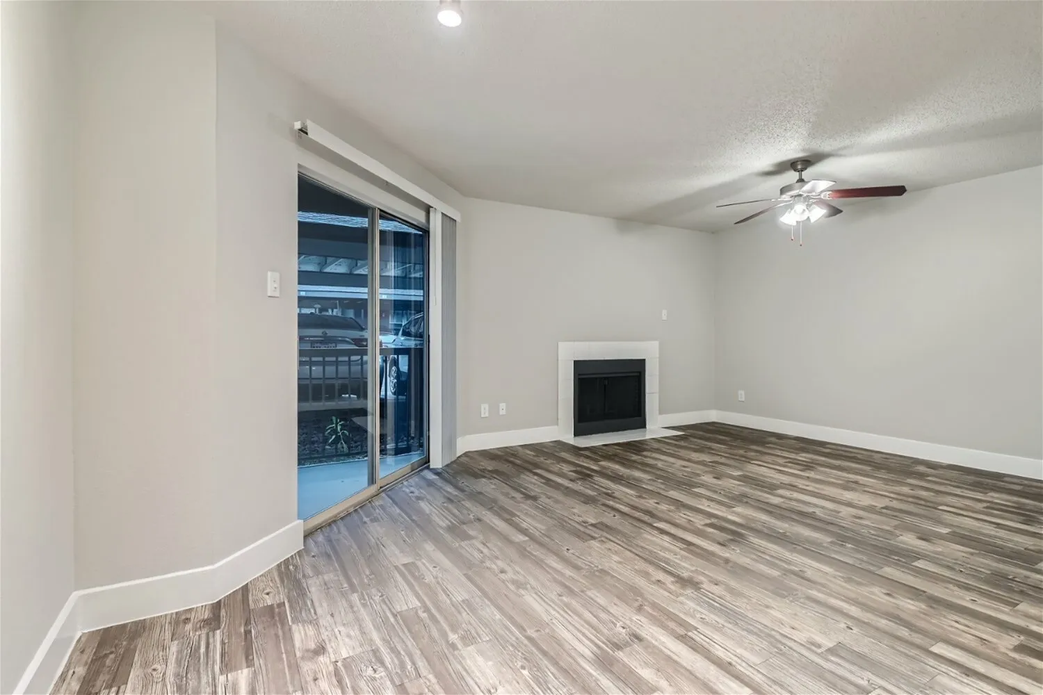 Living room, sliding glass door, fireplace, ceiling fan, wood-style plank flooring