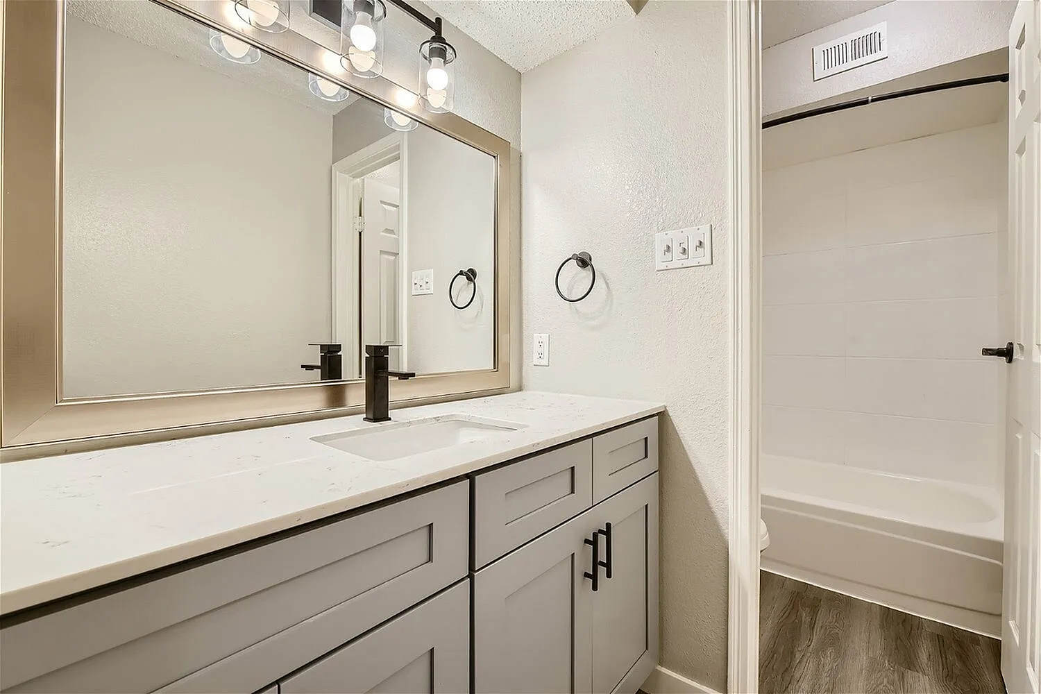 Bathroom vanity, framed mirror, black faucet, quartz-style countertop, gray shaker-style cabinet