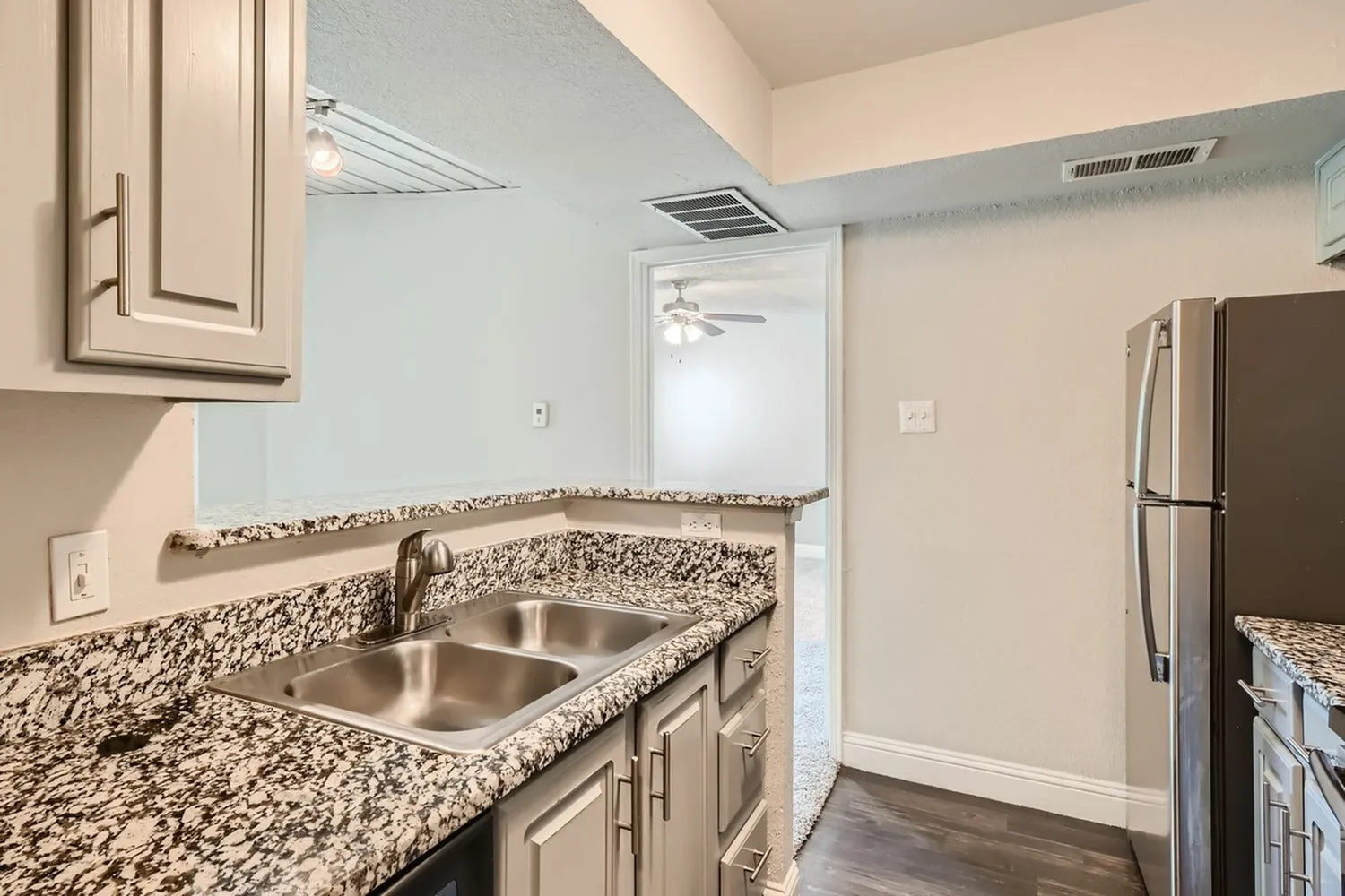 Double basin stainless steel sink, speckled countertop, peninsula, view to hallway