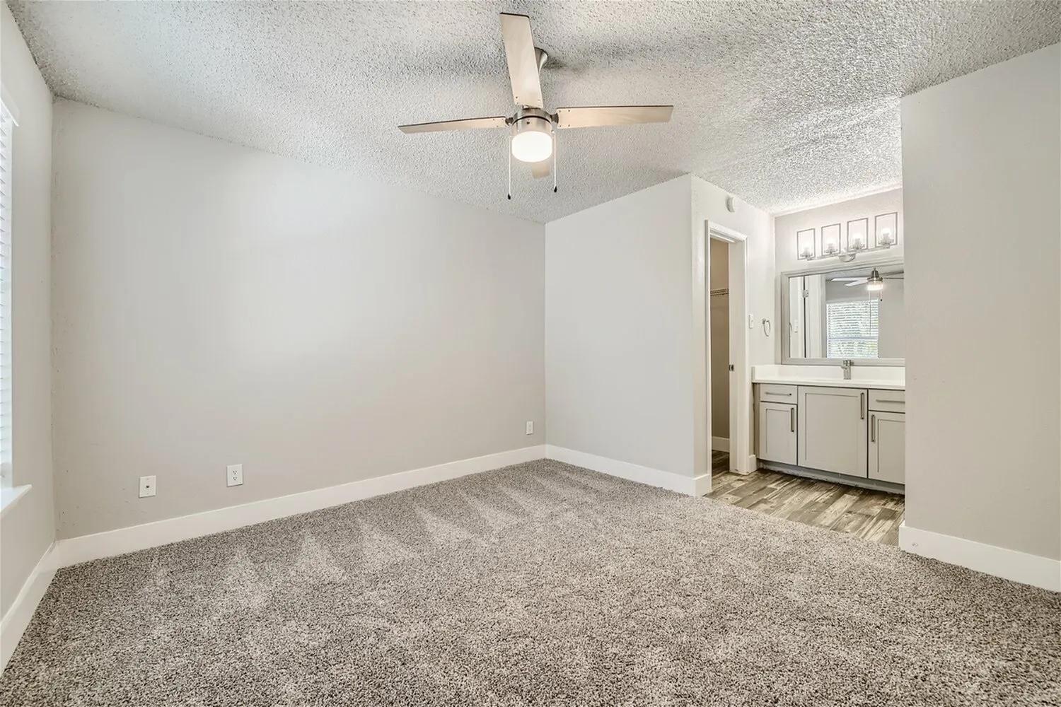 Bedroom, ceiling fan, carpet flooring, view to bathroom vanity