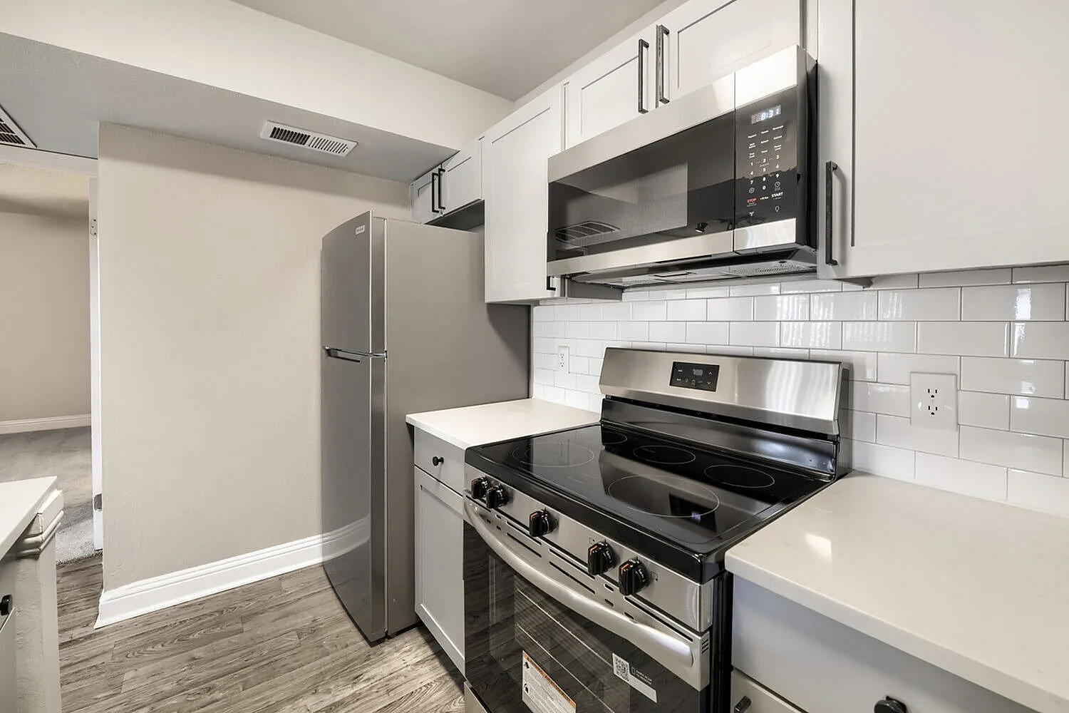 Stainless steel refrigerator, over-range microwave, smooth-top range, subway tile backsplash