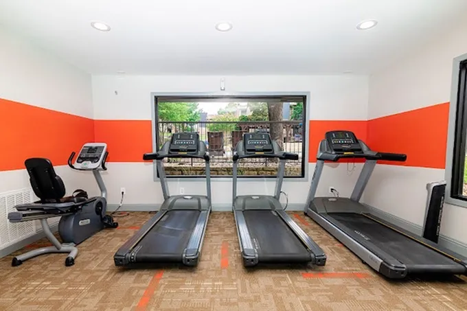 Fitness center, treadmills, large window, orange accent stripe, patterned carpet tile flooring
