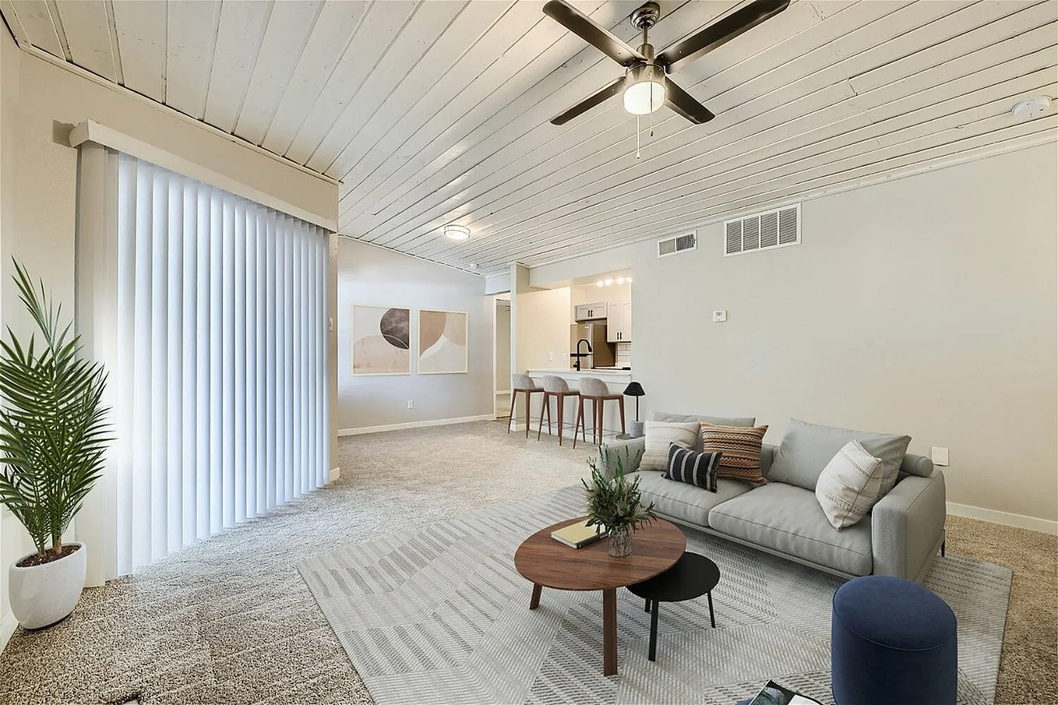 Open living and dining area, plank ceiling, vertical blinds, breakfast bar, carpet flooring