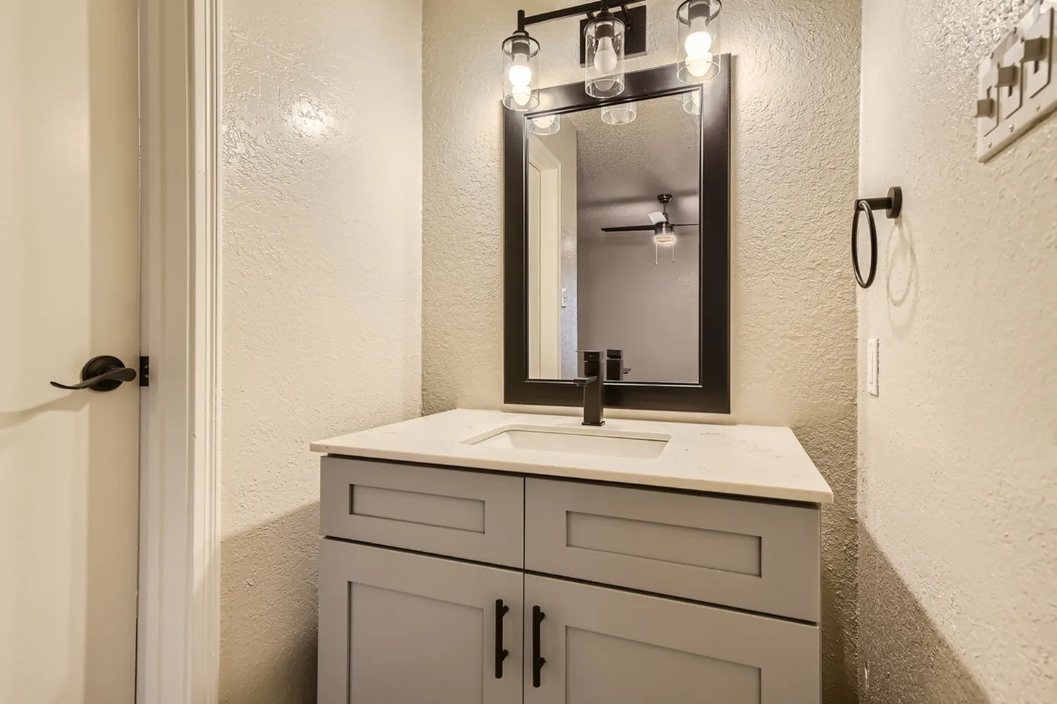 Single vanity, black framed mirror, white countertop, gray shaker-style cabinet