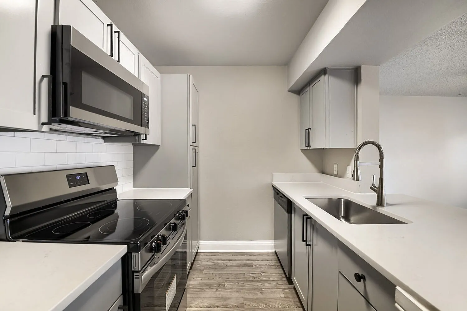 Stainless steel microwave, glass-top range, subway tile backsplash, undermount sink, dishwasher