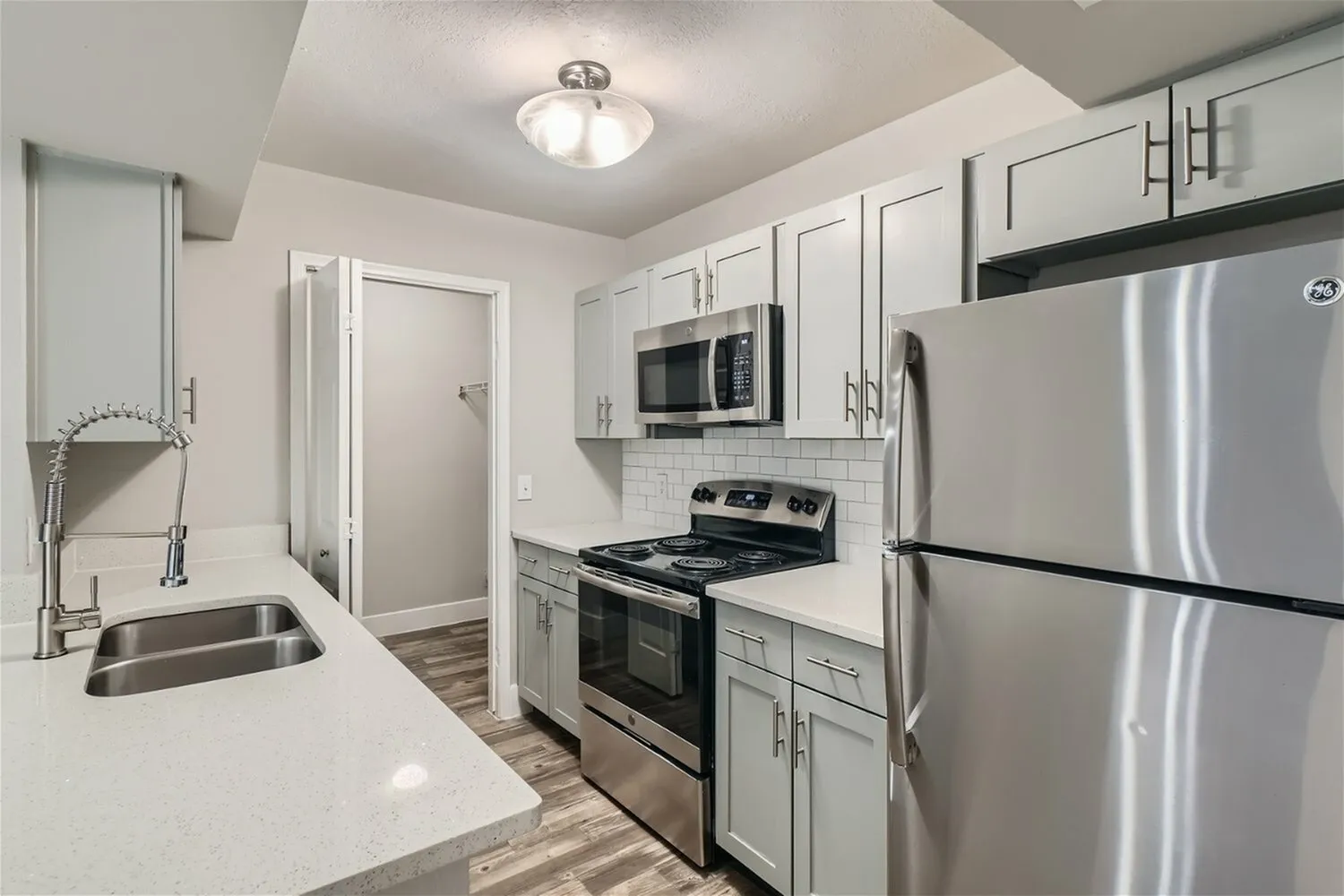 Kitchen, gray shaker-style cabinetry, stainless steel appliances, subway tile backsplash, quartz-style countertops