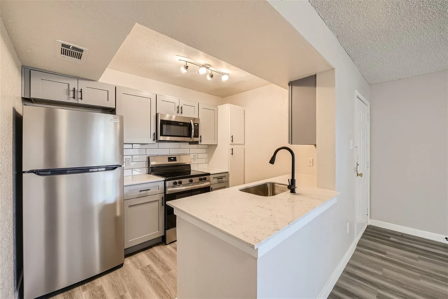 Kitchen, gray cabinetry, quartz-style countertops, subway tile backsplash, stainless steel appliances, track lighting