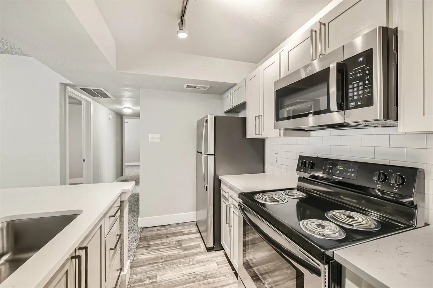 Stainless steel refrigerator, over-range microwave, electric coil range, subway tile backsplash