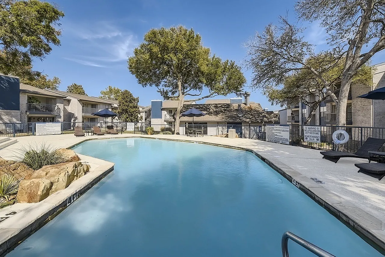 Pool, rock accents, pool deck, patio umbrellas, mature trees