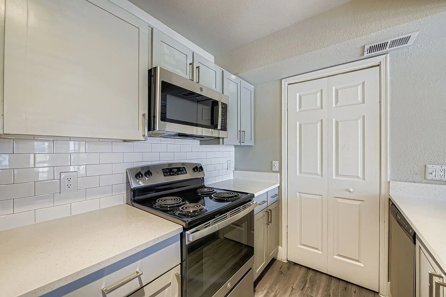 Stainless steel microwave, electric coil range, subway tile backsplash, pantry doors