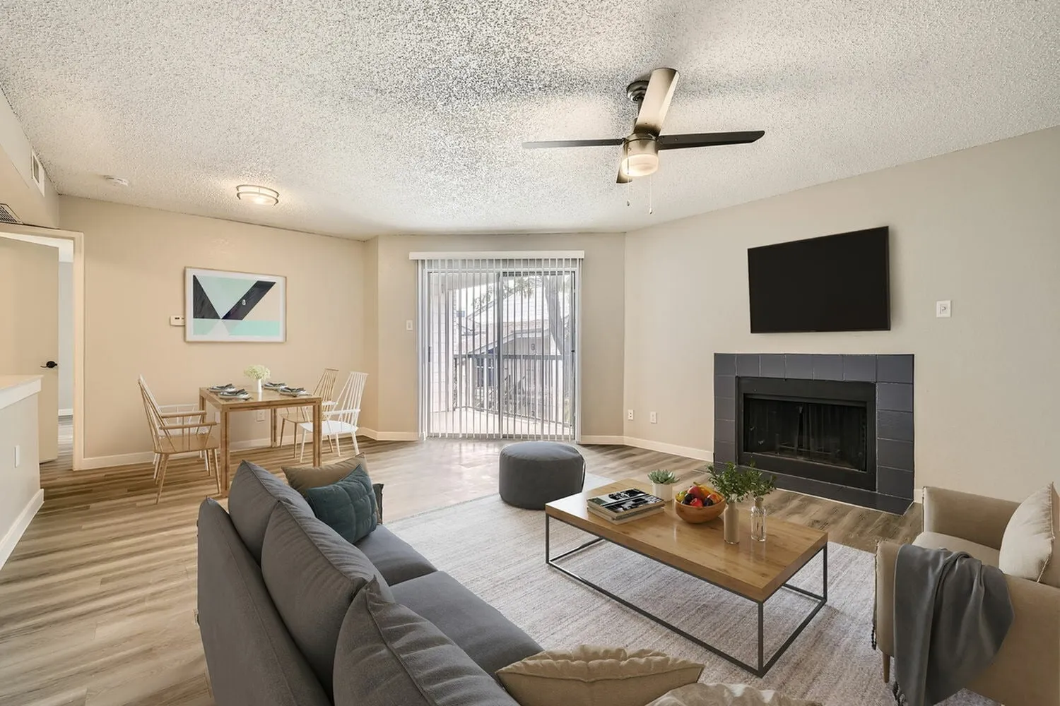 A2 Platinum living room, fireplace, ceiling fan, sliding glass door with vertical blinds, wood-style plank flooring