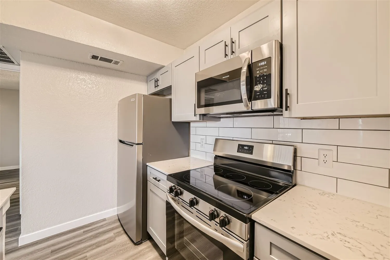 Stainless steel refrigerator, over-range microwave, smooth-top range, tile backsplash
