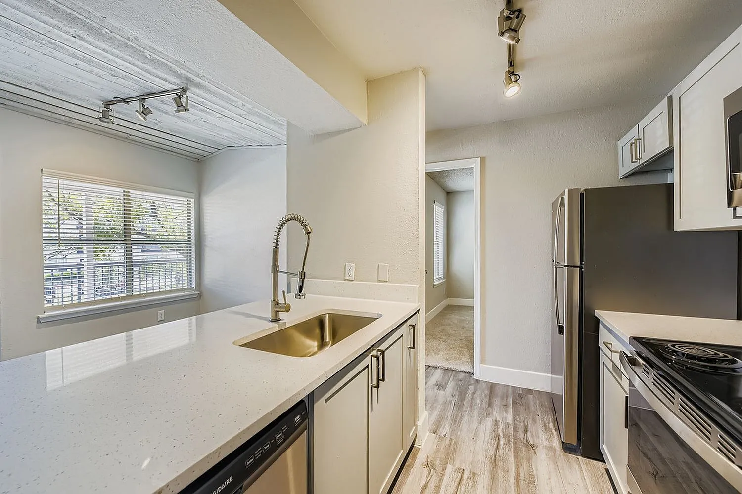 Undermount sink, pull-down faucet, quartz-style countertop, window, plank ceiling