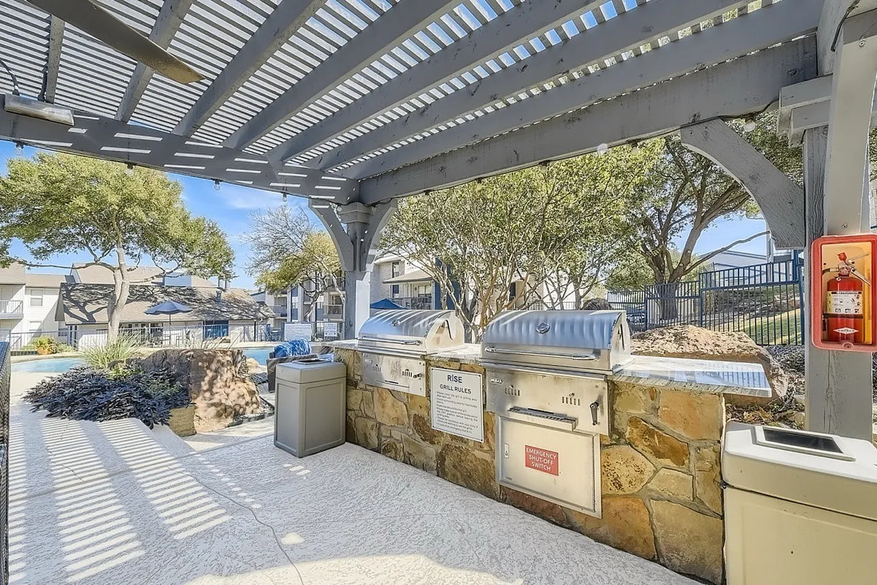Outdoor grills, stone-clad counter, pergola, pool deck