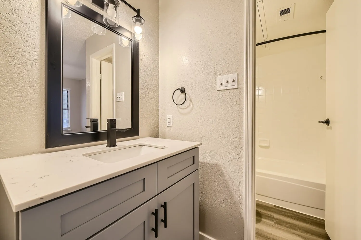 Bathroom vanity, black framed mirror, black faucet, white countertop, gray cabinet