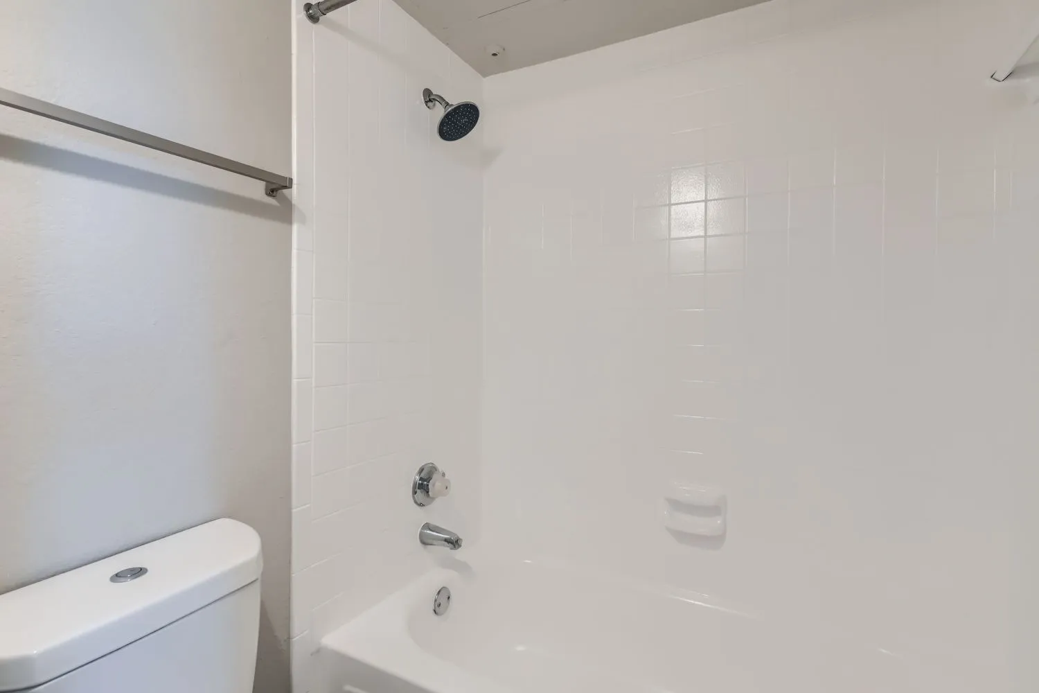 Tub shower, white tile surround, white toilet