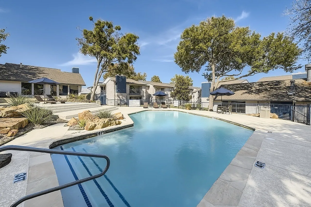 Pool with handrail entry, pool deck, rock accents, building exteriors