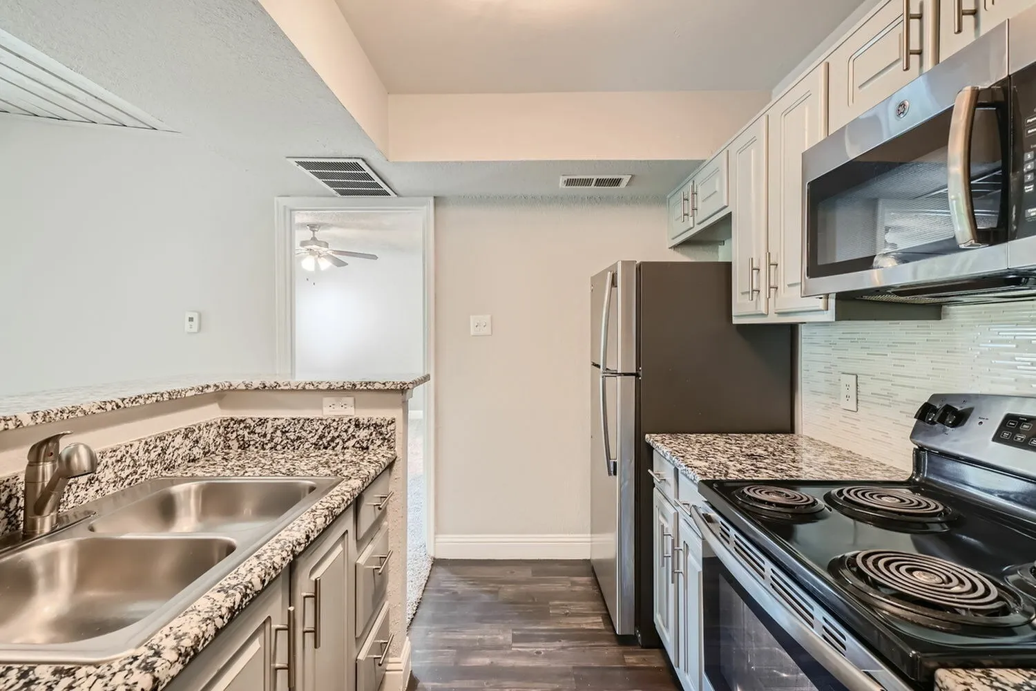 Stainless steel refrigerator, electric coil range, over-range microwave, speckled countertop