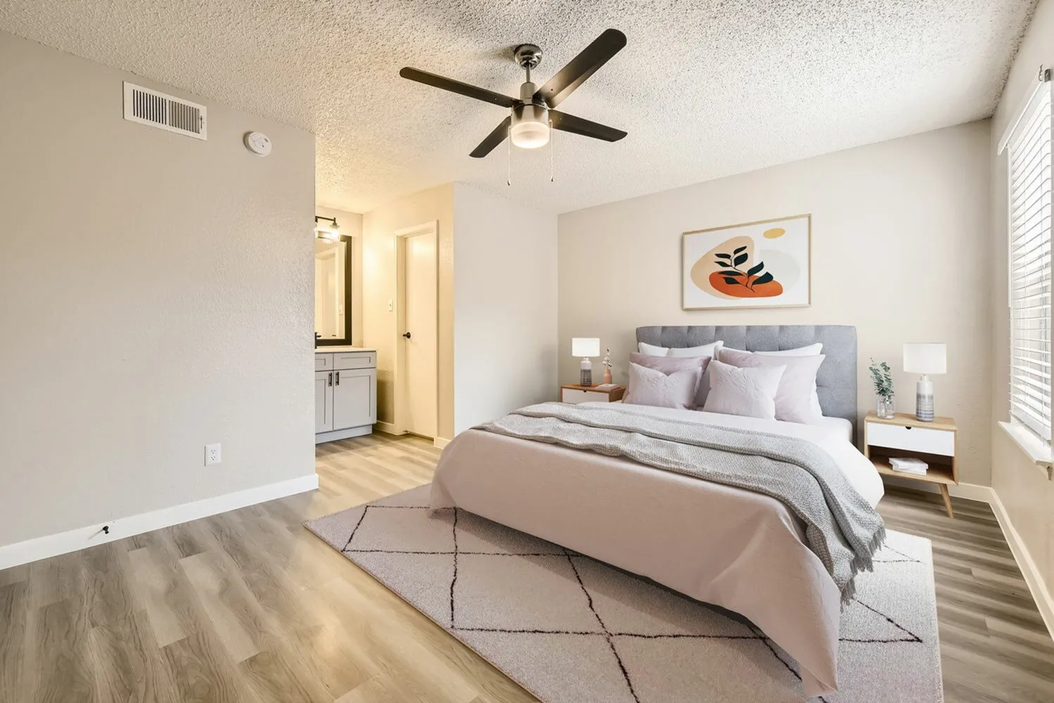 Bedroom, ceiling fan, wood-style plank flooring, view to bathroom