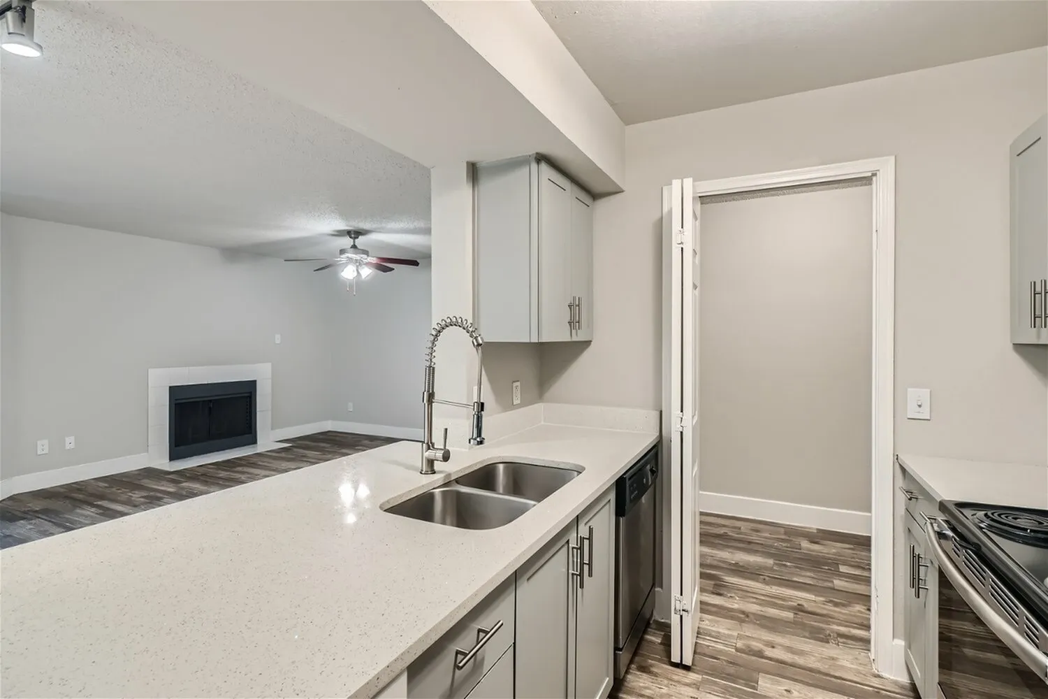Double basin sink, pull-down faucet, quartz-style countertop, dishwasher, view to fireplace